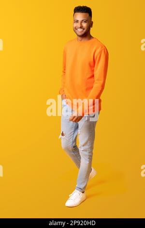 Foto in voller Länge von einem jungen, lächelnden, glücklichen indianer, 20s Mann in legerer Kleidung isoliert auf einfarbiger gelber Farbe, einem gutaussehenden arabischen Mann, der mit einem attraktiven Lächeln in die Kamera schaut Stockfoto
