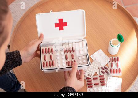 Nicht wiedererkennbarer Mann, der Medizin aus der offenen Apotheke am Tisch nimmt Stockfoto