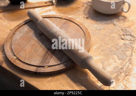 Der hölzerne Rollstift befindet sich auf einer runden Platte, Backgeräte Nahaufnahme mit selektivem Weichzeichner Stockfoto