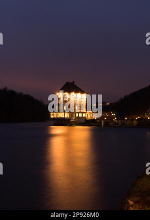 Der Rheinfall und die Burg am Rhein in der Abenddämmerung mit goldenen Lichtern und langzeitigem Porträtblick Stockfoto