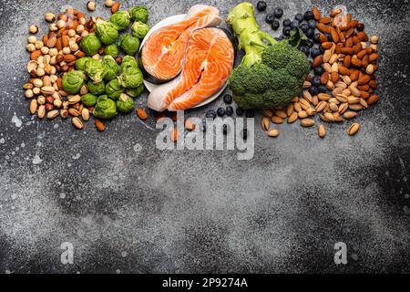 Verschiedene Lebensmittel für die Gesundheit des Gehirns und gutes Gedächtnis: Frischer Lachs, Gemüse, Nüsse, Beeren auf Stein Hintergrund. Gesunde frische Produkte, um das Gehirn anzukurbeln Stockfoto