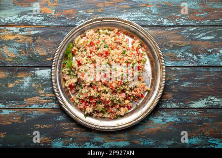 Nahöstlicher und mediterraner traditioneller Gemüsesalat Tabbouleh mit Couscous auf rustikaler Metallplatte und hölzernem Hintergrund von oben. Araber Stockfoto