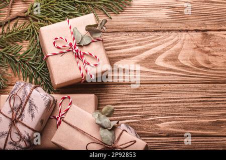 Das Weihnachtsgeschenk ist flach und mit Tannenzweig auf Holzhintergrund. Geschenkboxen für Weihnachten und Neujahr, Draufsicht mit freiem Platz Stockfoto