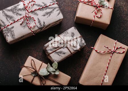 Minimalistisches Weihnachtsfest mit flacher Laienzusammensetzung auf dunklem Betonhintergrund. Weihnachten und Neujahr elegante Geschenkboxen, Draufsicht Stockfoto