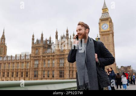 Ein fröhlicher Mann, der am Telefon vor dem Hintergrund von Londons Big Ben spricht Stockfoto