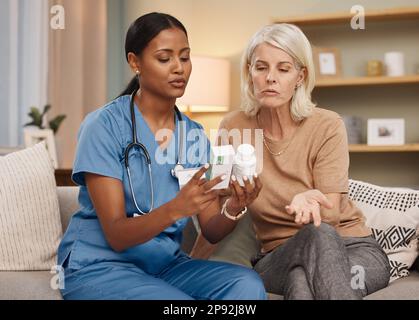 Bleiben Sie zu Hause und lassen Sie sich gut versorgen. Aufnahme eines Arztes, der während einer Konsultation mit einer älteren Frau zu Hause über Medikamentenoptionen diskutiert. Stockfoto