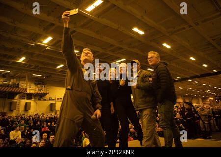 Captain Dave Pollard, befehlshabender Offizier an Bord des Flugzeugträgers USS George H.W. der Nimitz-Klasse Bush (CVN 77), macht ein Selfie auf der Bühne mit Tom Cruise, Right, Christopher McQuarrie, Center Right, Hannah Waddingham, Center, Eddie Hamilton, Left Center, Rear ADM. Dennis Velez, Commander Carrier Strike Group (CSG) 10 und George H.W. Bush CSG und Matrosen während eines Besuchs des Schiffs am 2. März 2023, während sie Szenen für „Mission: Impossible - Dead Reckoning Part Two“ drehten. Die George H.W. Die Bush Carrier Strike Group ist in den USA stationiert Marinestreitkräfte Europa Einsatzgebiet Stockfoto