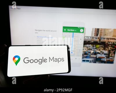 Person, die ein Smartphone mit dem Logo der Web-Mapping-Plattform Google Maps auf dem Bildschirm vor der Website hält. Konzentrieren Sie sich auf das Display des Telefons. Stockfoto