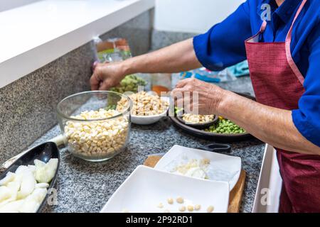 Unbekannte Frau, die Hülsenfrüchte kocht, um Fanesca zu kochen Stockfoto