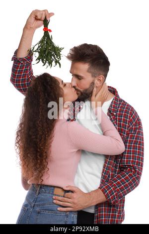 Ein glückliches Paar küsst sich unter Mistelzweigen auf weißem Hintergrund Stockfoto