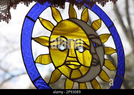 Ein Buntglasstück aus Sonne und Mond hängt im Küchenfenster. Stockfoto
