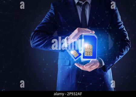Ein Mann, der SIM-Karten verschiedener Größen auf dunklem Hintergrund vorführt, Nahaufnahme Stockfoto