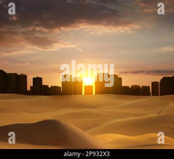 Sandwüste und Silhouette der Stadt am Horizont bei Sonnenuntergang Stockfoto