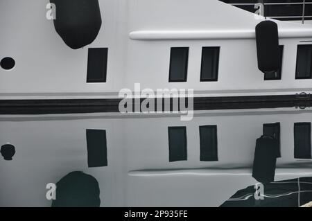 Yachtboot im Hafen von Rijeka. Weiße Yacht mit schwarzen Fenstern, die auf die Meeresoberfläche reflektiert werden. Stockfoto