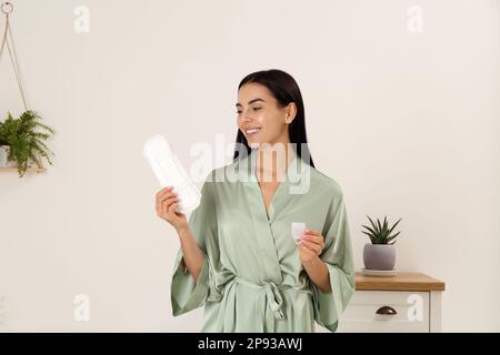 Junge Frau mit Menstruationsbecher und -Pad zu Hause Stockfoto