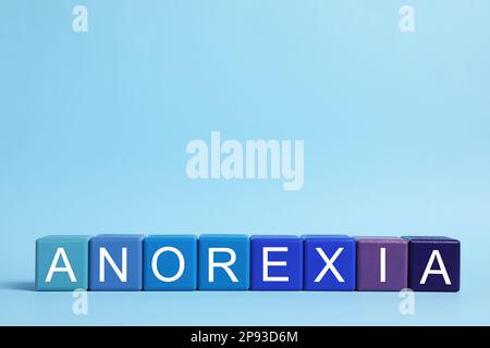 Word Anorexia aus bunten Würfeln mit Buchstaben auf hellblauem Hintergrund Stockfoto