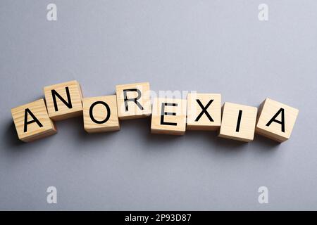 Word Anorexia aus Holzwürfeln mit Buchstaben auf hellgrauem Hintergrund, flach liegend Stockfoto