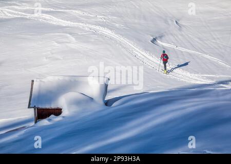 Italien, Veneto, Provinz Belluno, Livinallongo del Col di Lana, Bergsteiger bergauf Richtung Sief Saddle, vorbei an einer schneebedeckten Holzhütte, Dolomiten Stockfoto