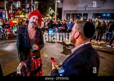 Tel Aviv, Israel. 10. März 2023. Ein Mann, der als Frau für Purim verkleidet ist, spricht mit einem orthodoxen jüdischen Mann nach einem Schussanschlag auf die Dizingof Street. Die militante palästinensische Gruppe Hamas hat sich für den Terroranschlag in Tel Aviv am Donnerstagabend verantwortlich gemacht, bei dem drei Israelis verletzt wurden. Der Angriff im Herzen der Stadt erfolgte nach einem Tag des Protests der israelischen Opposition gegen Netanjahus Regierung. Kredit: SOPA Images Limited/Alamy Live News Stockfoto