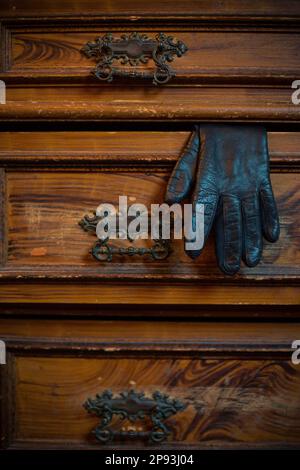 Ein Lederhandschuh auf einer alten Holzkleide Stockfoto