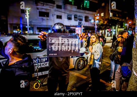 Tel Aviv, Israel. 10. März 2023. Ein maskierter rechter Aktivist hält ein Plakat, auf dem steht: „ Es gibt keine Koexistenz mit dem Feind“ nach einem Terroranschlag auf die Dizingof Street. Die militante palästinensische Gruppe Hamas hat sich für den Terroranschlag in Tel Aviv am Donnerstagabend verantwortlich gemacht, bei dem drei Israelis verletzt wurden. Der Angriff im Herzen der Stadt erfolgte nach einem Tag des Protests der israelischen Opposition gegen Netanjahus Regierung. (Foto: Eyal Warshavsky/SOPA Images/Sipa USA) Guthaben: SIPA USA/Alamy Live News Stockfoto