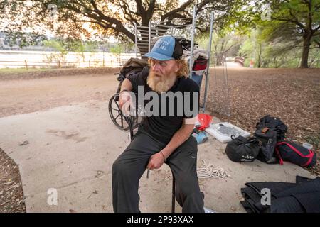 Austin, Texas, USA. 9. März 2023. Ein Obdachloser, der nicht identifiziert werden wollte, sitzt am 9. März 2023 bei den meisten seiner Sachen auf dem Wander- und Radweg entlang der Nordküste des Lady Bird Lake in der Innenstadt von Austin. Der Mann, der seit etwa 9 Monaten an der Küste zeltet, wurde schließlich von Crews gebeten, zu gehen, die einen geteilten Zaun bauen und Beleuchtung hinzufügen, nachdem er kürzlich ertrunken war. (Kreditbild: © Bob Daemmrich/ZUMA Press Wire) NUR REDAKTIONELLE VERWENDUNG! Nicht für den kommerziellen GEBRAUCH! Stockfoto