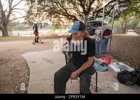 Austin, Texas, USA. 9. März 2023. Ein Obdachloser, der nicht identifiziert werden wollte, sitzt am 9. März 2023 bei den meisten seiner Sachen auf dem Wander- und Radweg entlang der Nordküste des Lady Bird Lake in der Innenstadt von Austin. Der Mann, der seit etwa 9 Monaten an der Küste zeltet, wurde schließlich von Crews gebeten, zu gehen, die einen geteilten Zaun bauen und Beleuchtung hinzufügen, nachdem er kürzlich ertrunken war. (Kreditbild: © Bob Daemmrich/ZUMA Press Wire) NUR REDAKTIONELLE VERWENDUNG! Nicht für den kommerziellen GEBRAUCH! Stockfoto