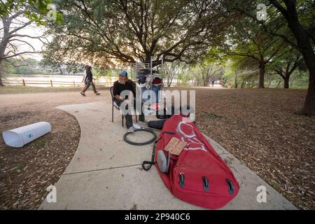 Austin, Texas, USA. 9. März 2023. Ein Obdachloser, der nicht identifiziert werden wollte, sitzt am 9. März 2023 bei den meisten seiner Sachen auf dem Wander- und Radweg entlang der Nordküste des Lady Bird Lake in der Innenstadt von Austin. Der Mann, der seit etwa 9 Monaten an der Küste zeltet, wurde schließlich von Crews gebeten, zu gehen, die einen geteilten Zaun bauen und Beleuchtung hinzufügen, nachdem er kürzlich ertrunken war. (Kreditbild: © Bob Daemmrich/ZUMA Press Wire) NUR REDAKTIONELLE VERWENDUNG! Nicht für den kommerziellen GEBRAUCH! Stockfoto