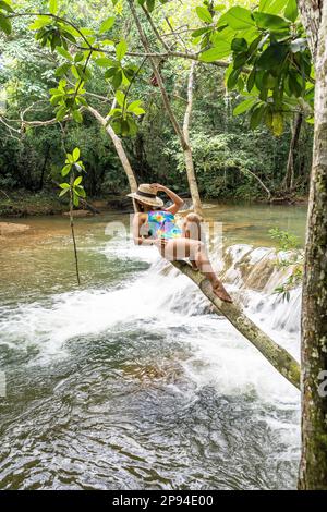 Nordamerika, Karibik, Großantillen, Hispaniola, Dominikanische Republik, Monte Plata Province, Bayaguana, attraktive Latina liegt auf einem stabilen Zweig über dem Fluss Stockfoto