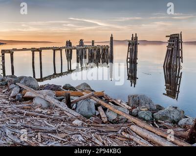 Die Sonne geht gleich über den Horizont über einem alten Fischerpier auf San Juan Island auf. Stockfoto