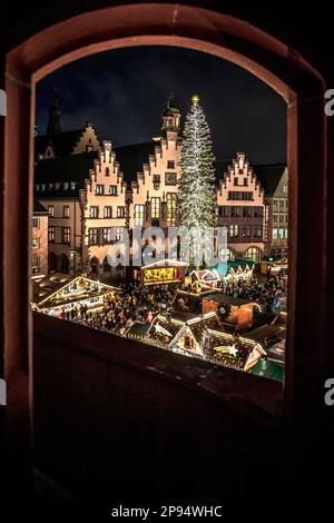 Blick durch einen Bogen auf den Weihnachtsmarkt am Römerberg. Schöne Beleuchtung, im Rathaus von Frankfurt am Main, Hessen, Deutschland Stockfoto