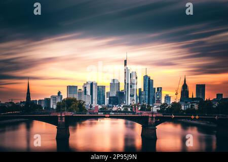 Blick von der Flöserbrücke in Frankfurt am Main, Hessen, Deutschland, über den Main bis zur Skyline, dem Bankenviertel und dem Stadtzentrum. Sonnenuntergang mit Abendrot Stockfoto