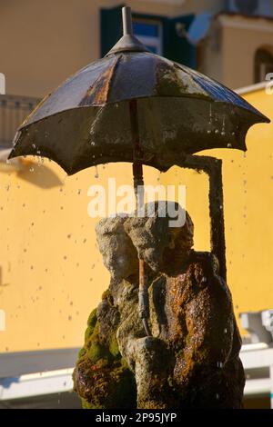 Amalfi Stadt. Fontana degli Innamorati. Dies ist der Brunnen der Liebe, der ein junges Paar darstellt, das sich im Regen umarmt. Das Wasser fließt aus der Spitze des offenen Schirms. Amalfiküste, Salerno, Italien Stockfoto