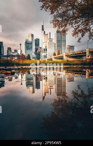 Reflexionen in Frankfurt am Main. Die Stadt, Straßen und Wolkenkratzer spiegeln sich nach Regen in den Pfützen der Straßen wider. Bankenviertel und Wolkenkratzer am Morgen Stockfoto