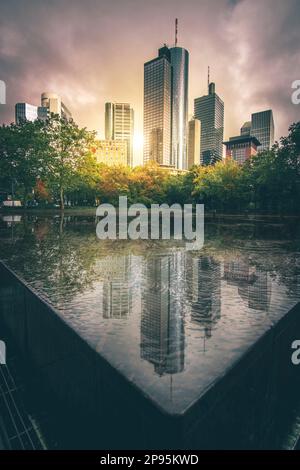 Reflexionen in Frankfurt am Main. Die Stadt, Straßen und Wolkenkratzer spiegeln sich nach Regen in den Pfützen der Straßen wider. Bankenviertel und Wolkenkratzer am Morgen Stockfoto