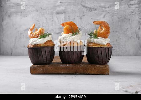 Drei leckere Muffins mit Garnelen und Käse auf grauem Hintergrund, Kopierraum Stockfoto