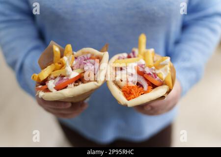 Eine Frau hält ein Paar Gyros in Pita-Brot. Eine weibliche Person bringt traditionelles griechisches Fast Food zum Mittagessen mit. Globales Küchenkonzept Stockfoto