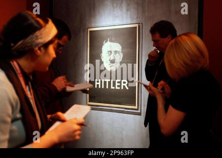 Reporters take notes in front of a Nazi party election poster from 1932, during a media tour of the exhibit, 'State of Deception: The Power of Nazi Propaganda,' at the National Holocaust Museum in Washington, on Wednesday, Feb. 4, 2009. (AP Photo/Jacquelyn Martin)