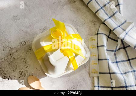 Lunchbox aus Kunststoff mit Bento-Kuchen und gelbem Band auf weißem Hintergrund. Torte for Valentine's Day, Mother's Day, oder Birthday, Love Forever Message, RO Stockfoto