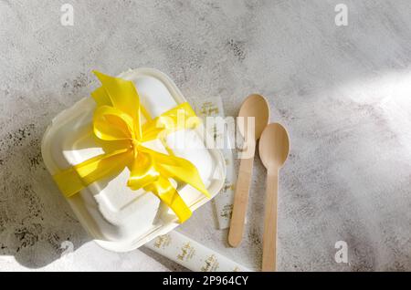 Lunchbox aus Kunststoff mit Bento-Kuchen und gelbem Band auf weißem Hintergrund. Torte for Valentine's Day, Mother's Day, oder Birthday, Love Forever Message, RO Stockfoto