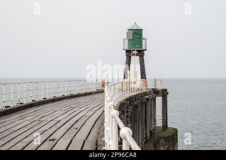 Das grün bemalte Leuchtfeuer am Ende des geschwungenen Piers in Whitby. Rote und grüne Lichter sind an den bemalten Türmen am Ende jedes Piers befestigt Stockfoto