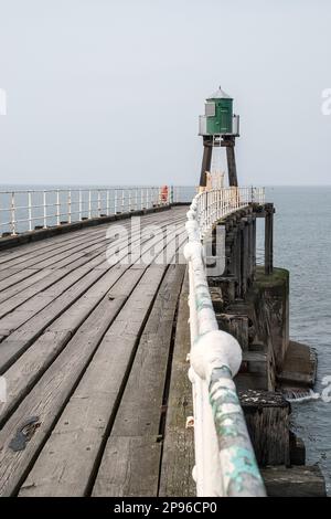 Das grün bemalte Leuchtfeuer am Ende des geschwungenen Piers in Whitby. Rote und grüne Lichter sind an den bemalten Türmen am Ende jedes Piers befestigt Stockfoto