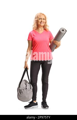 Ganzlängenporträt einer erwachsenen Frau in Sportkleidung mit einer Trainingsmatte und einer Sporttasche isoliert auf weißem Hintergrund Stockfoto