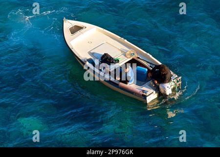 Kleines Boot mit Außenbordmotor im Meer vor Positano, Salerno, Italien, mit Blick von oben auf das klare, blaue Wasser des Tyrrhenischen Meeres, Mittelmeer. Stockfoto