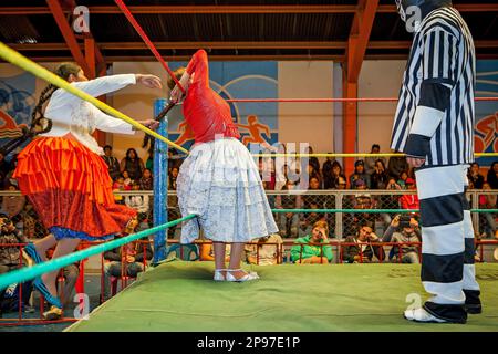 Lucha Libre. Kampf zwischen Dina mit orangefarbenem Rock und Benita la Intocable, Cholitas-Frauen-Ringer, mit Schiedsrichter, Sportzentrum La Ceja, El Alto, Stockfoto