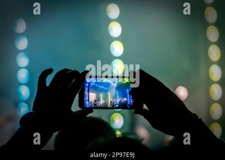 Junge Leute machen Fotos oder Videos von einem Konzert auf Smartphones. Stockfoto