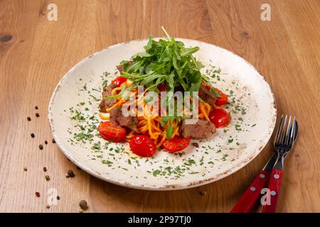 Köstliche klassische italienische Spaghetti La Carne mit Tomaten und Rucola. Serviert auf einem Holztisch. Normale Ansicht. Stockfoto