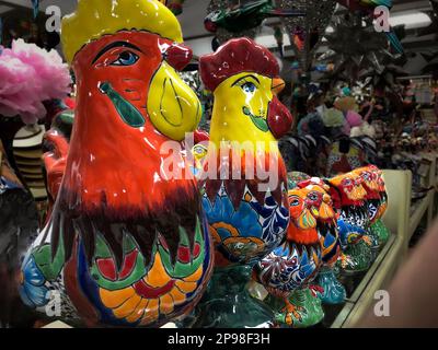 Viele bunt bemalte Keramikhühner hängen an der Wand und werden in einem mexikanischen Basar-Shop verkauft. Stockfoto