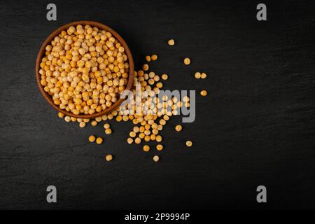 Getrocknete gelbe Erbsen auf schwarzem Hintergrund, ganze Erbspelze, rohes Hülsenfleisch, Proteinquelle, gesunde vegane Lebensmittel, Verstreute, trockene, gelbe Erbsen auf weißem Hintergrund Stockfoto