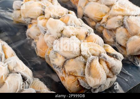 Verpackte Gefrorene Muscheln, Nicht Ausgelöste Muscheln, Gefrorene Geschälte Muscheln, Kalte Muscheln, Gefrorene Meeresfrüchte, Gekochte Schalentiere auf schwarzem Stein Hintergrund Nahaufnahme Stockfoto